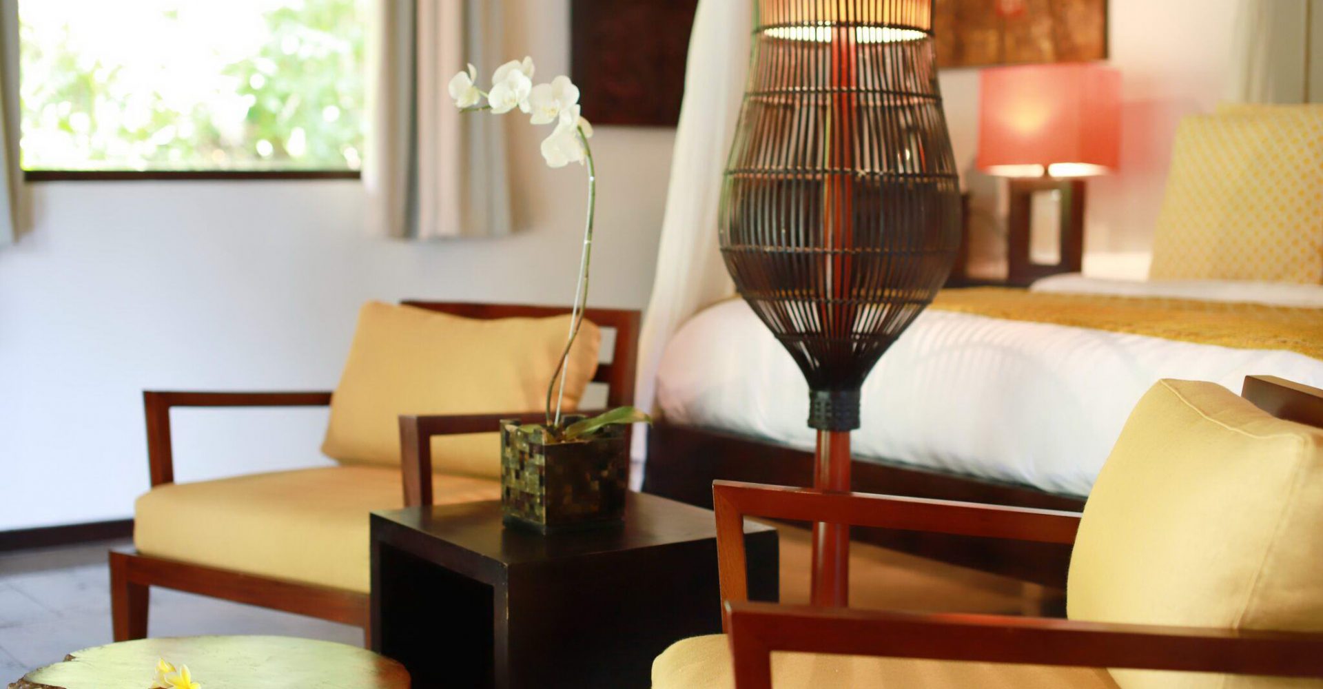 The seating area with lamp and orchid inside Sukavati's one bedroom luxury villa ‘White Tara'.